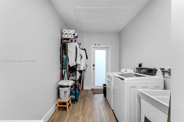 clothes washing area featuring light wood finished floors, washing machine and dryer, laundry area, and baseboards