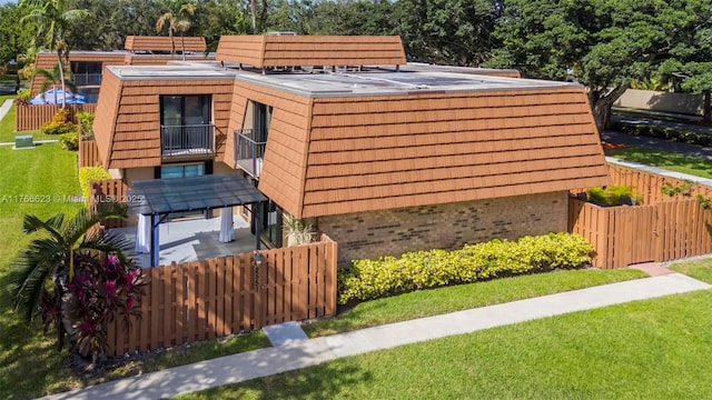 view of side of home featuring a yard, brick siding, and fence