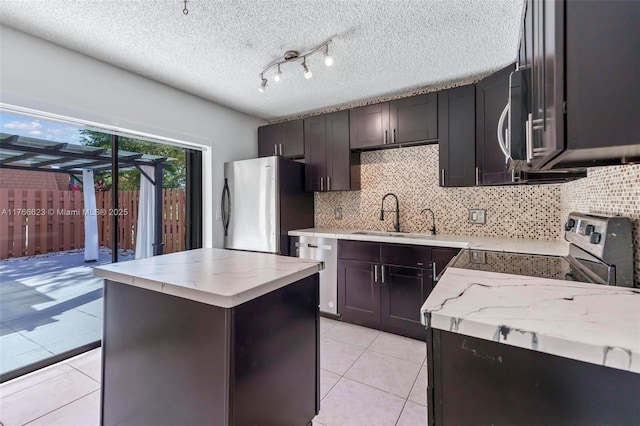 kitchen featuring a center island, light stone countertops, stainless steel appliances, and a sink