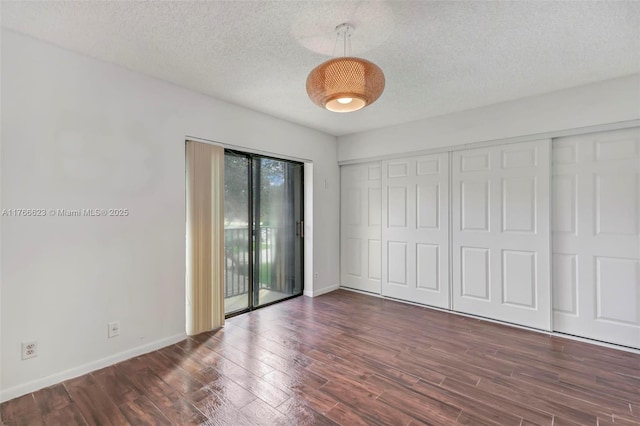unfurnished bedroom with baseboards, a textured ceiling, wood finished floors, and access to outside