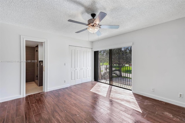 unfurnished bedroom with a textured ceiling, wood finished floors, baseboards, and access to outside
