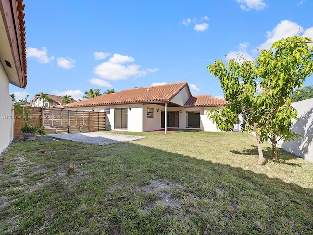 13481 SW 103rd St, Miami, FL 33186 - back of house featuring a fenced backyard, stucco siding, a tile roof, a patio area, and a lawn