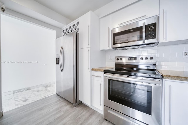 kitchen with white cabinets, tasteful backsplash, and stainless steel appliances