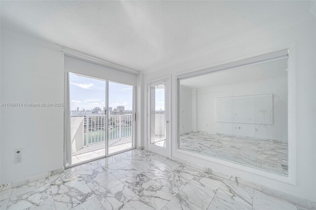 empty room featuring a city view, marble finish floor, and crown molding