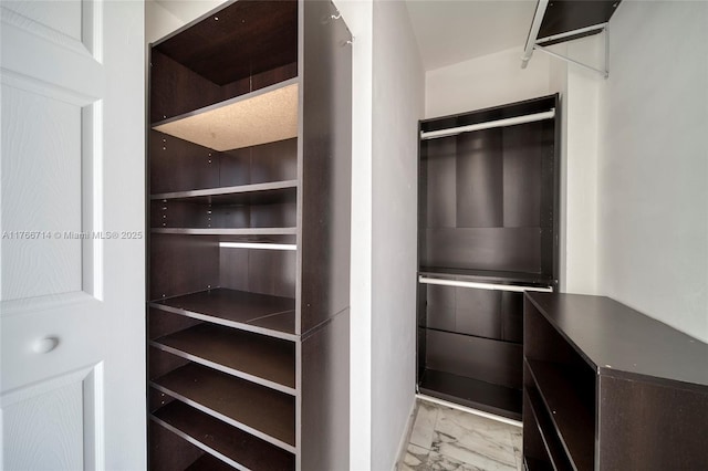 walk in closet featuring wine cooler and marble finish floor