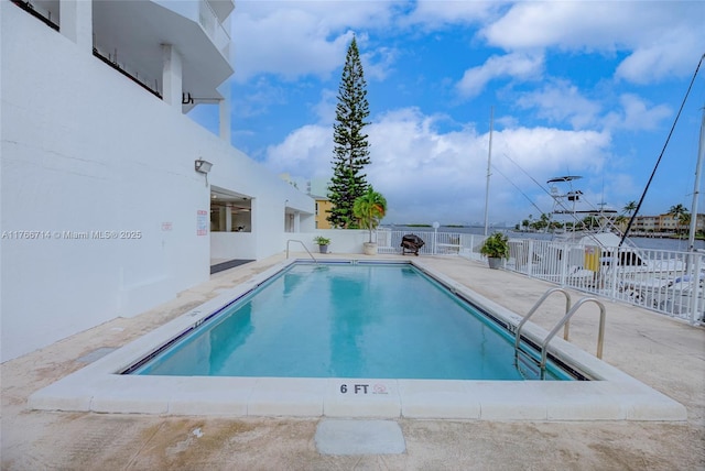 community pool with a patio area and fence