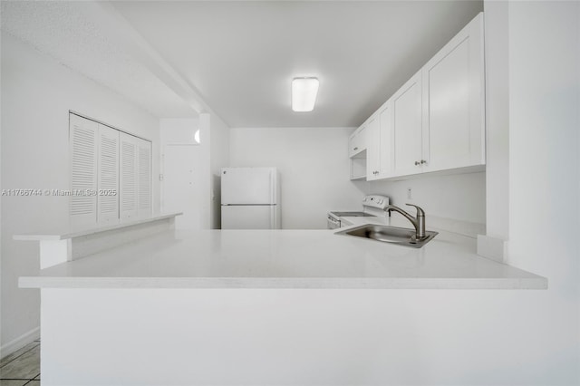 kitchen featuring a sink, white cabinetry, white appliances, a peninsula, and light countertops