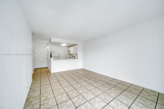 unfurnished living room with baseboards and a textured ceiling