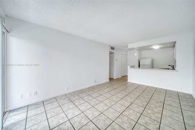unfurnished living room featuring a textured ceiling, baseboards, and a sink
