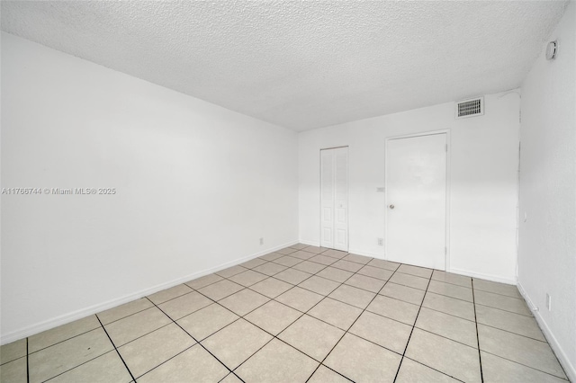 spare room featuring baseboards, visible vents, and a textured ceiling