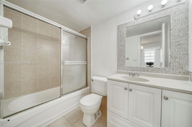 bathroom featuring vanity, enclosed tub / shower combo, tile patterned flooring, a textured ceiling, and toilet
