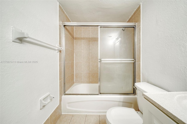 bathroom with enclosed tub / shower combo, toilet, vanity, and a textured wall
