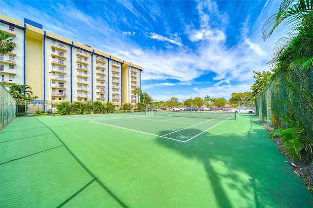 view of tennis court with community basketball court and fence