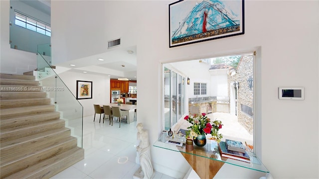 dining area with plenty of natural light, visible vents, a high ceiling, and stairway