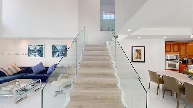 stairway featuring a high ceiling, tile patterned floors, and recessed lighting