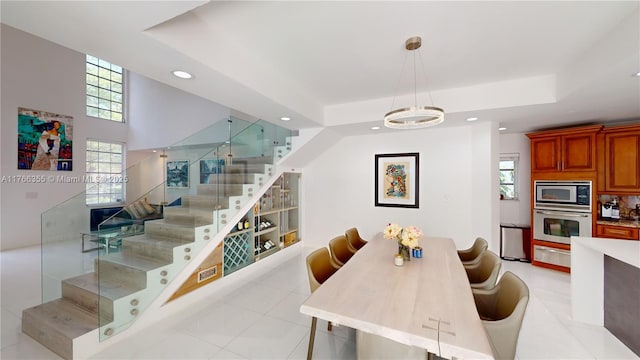 dining room with stairs, a tray ceiling, recessed lighting, and light tile patterned floors