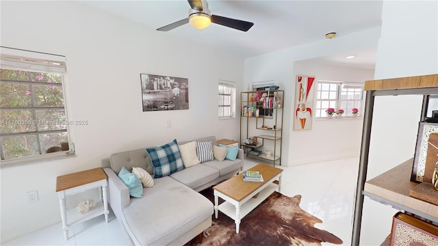 living area featuring baseboards and ceiling fan