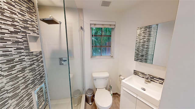 full bathroom featuring toilet, vanity, a shower stall, and visible vents