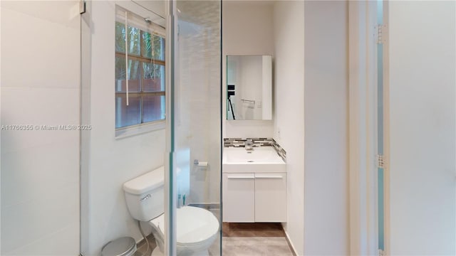 bathroom with toilet, backsplash, and vanity