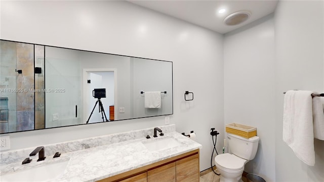 bathroom featuring a stall shower, double vanity, toilet, and a sink