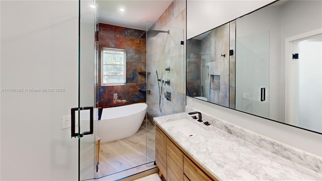 bathroom with tile walls, a freestanding tub, a stall shower, and vanity
