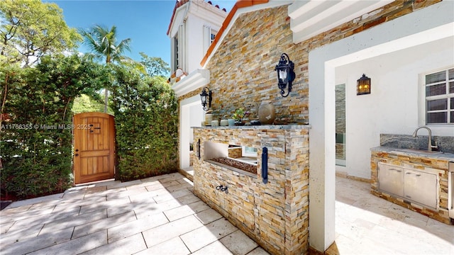 view of patio with a sink, a gate, and exterior kitchen