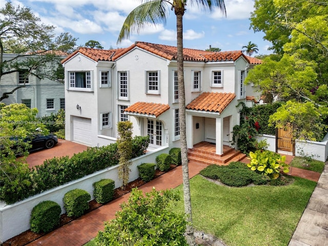 mediterranean / spanish-style house featuring a tile roof, concrete driveway, stucco siding, and an attached garage