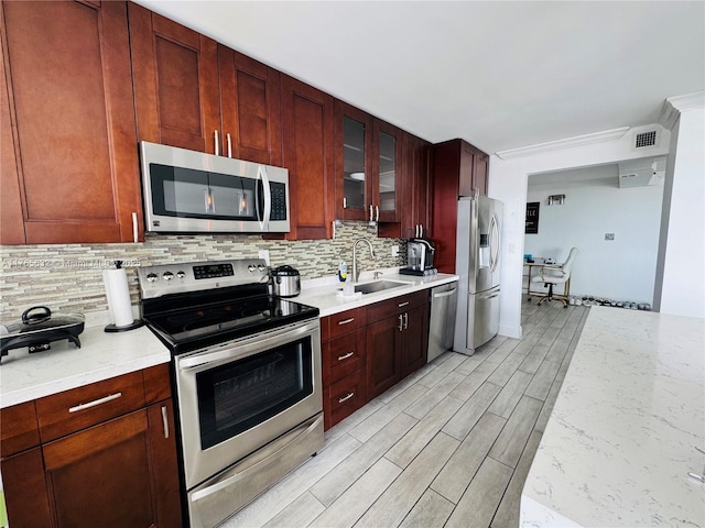 kitchen with a sink, backsplash, appliances with stainless steel finishes, glass insert cabinets, and wood finish floors