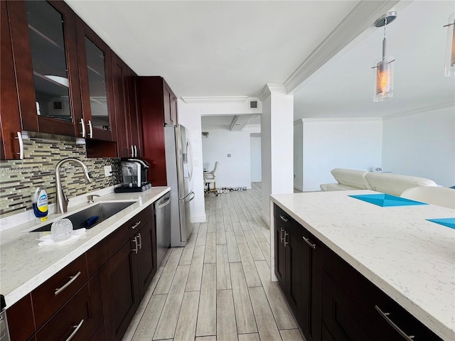 kitchen with decorative backsplash, appliances with stainless steel finishes, wood tiled floor, a sink, and decorative light fixtures