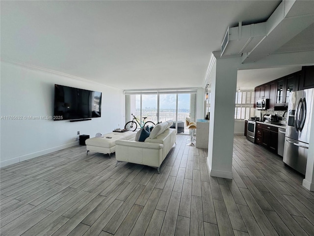 living area with baseboards, crown molding, and wood finished floors