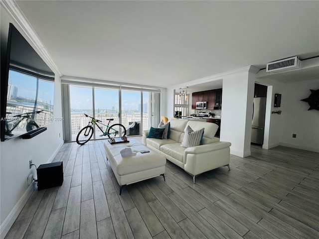 living room featuring baseboards, visible vents, crown molding, and wood finished floors