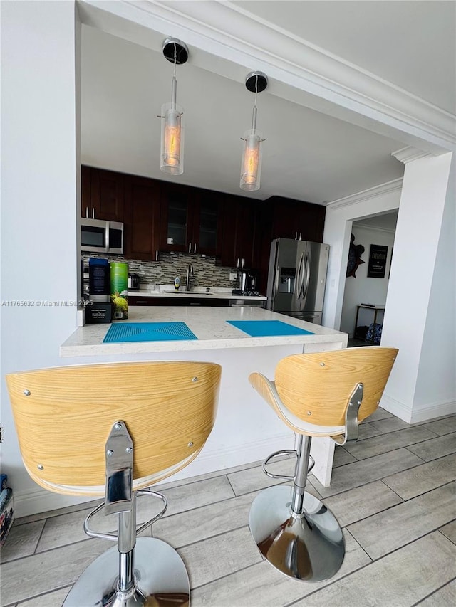 kitchen featuring decorative light fixtures, stainless steel appliances, baseboards, backsplash, and a sink