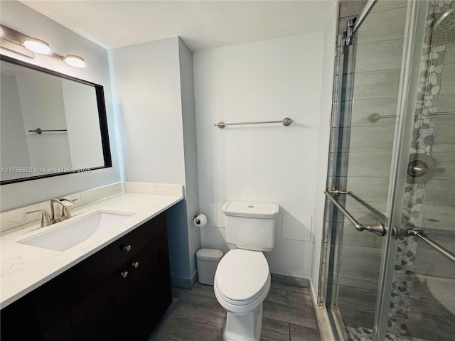 full bath featuring vanity, baseboards, toilet, and a shower stall