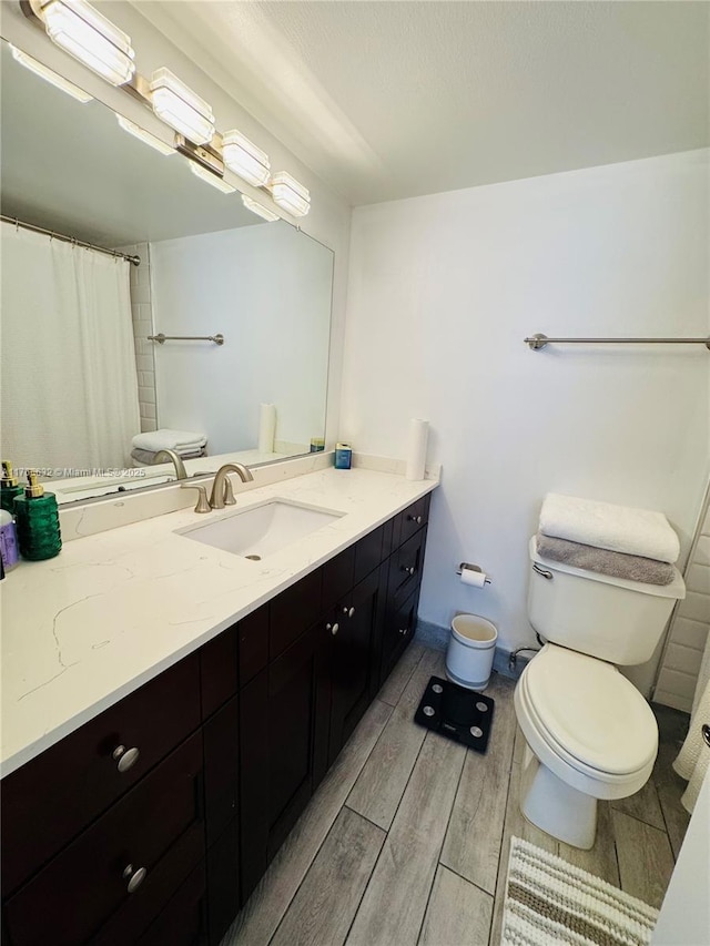 bathroom featuring curtained shower, wood tiled floor, toilet, and vanity