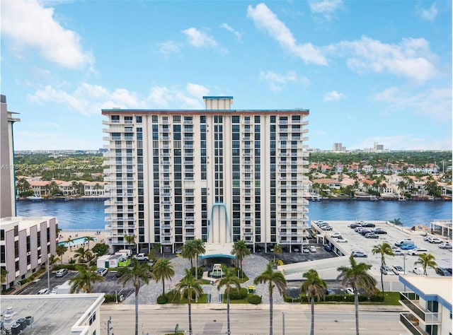 view of building exterior featuring a water view, uncovered parking, and a view of city