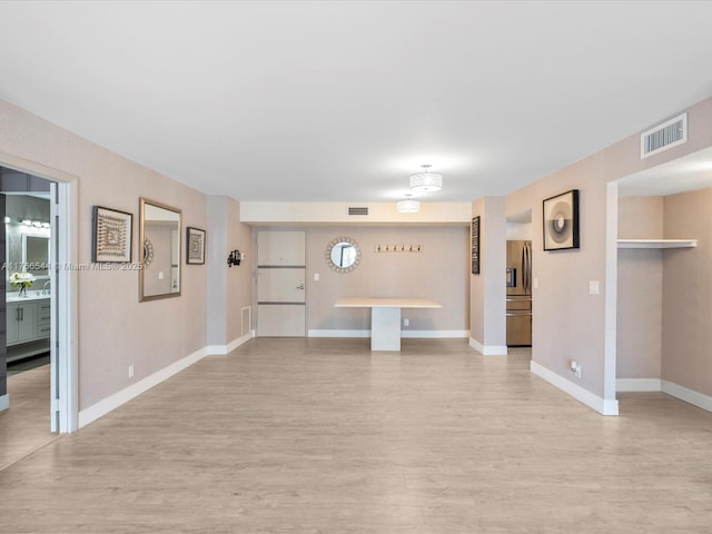 unfurnished living room with baseboards, visible vents, and light wood-type flooring
