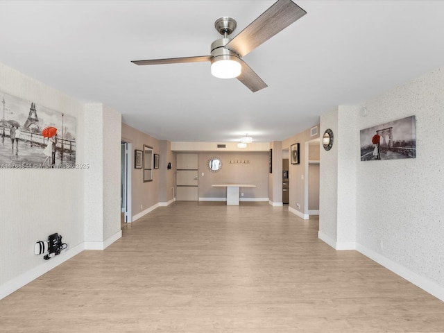 unfurnished living room featuring baseboards, a ceiling fan, and light wood finished floors