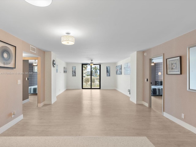 unfurnished living room with visible vents, radiator heating unit, light wood-style floors, and a ceiling fan