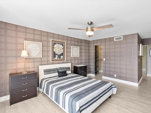 bedroom featuring a ceiling fan, wood finished floors, baseboards, and visible vents