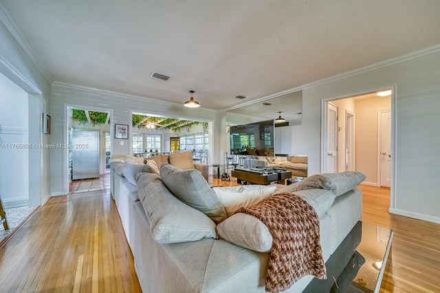 living room with baseboards, visible vents, light wood-style floors, and ornamental molding