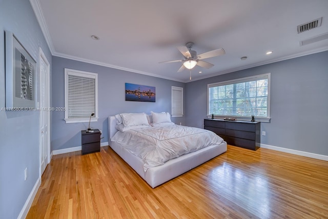 bedroom featuring baseboards, visible vents, crown molding, and light wood finished floors