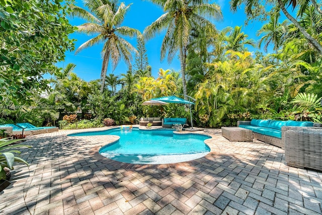 pool with an outdoor living space and a patio