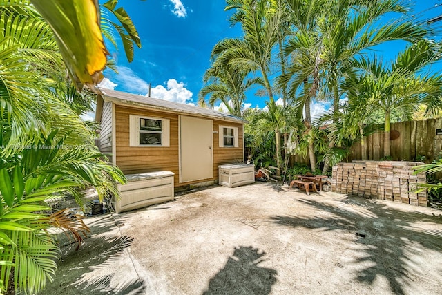 rear view of property featuring an outbuilding, fence, and a patio