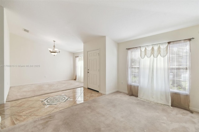 tiled empty room with an inviting chandelier, carpet flooring, visible vents, and baseboards