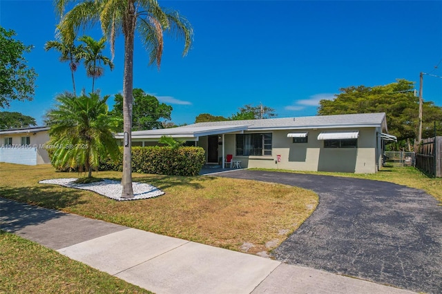 ranch-style house with a front lawn, fence, driveway, and stucco siding