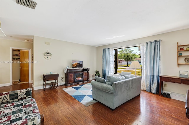 living room with visible vents, baseboards, and wood finished floors