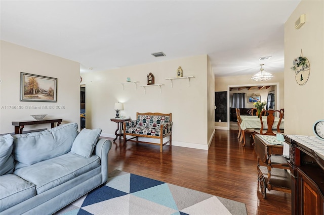 living room with visible vents, baseboards, a notable chandelier, and wood finished floors