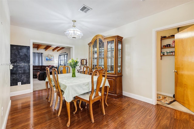 dining area with a chandelier, visible vents, beamed ceiling, and wood finished floors