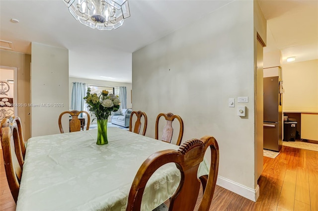 dining space featuring a notable chandelier, baseboards, and wood finished floors