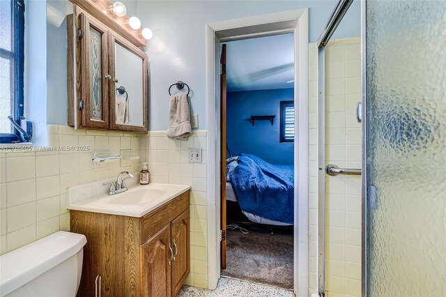 bathroom featuring vanity, speckled floor, ensuite bathroom, tile walls, and toilet